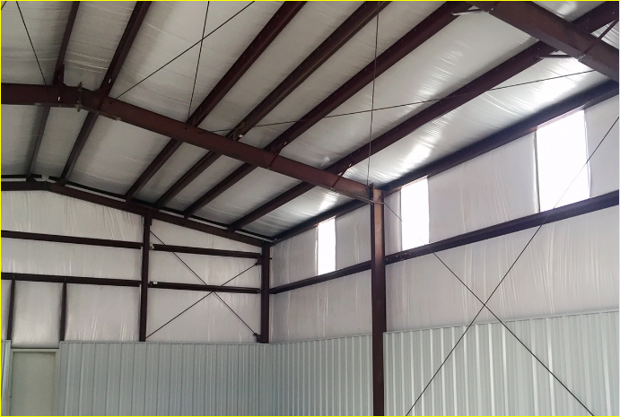 Steel building at dusk with interior lights through tall windows